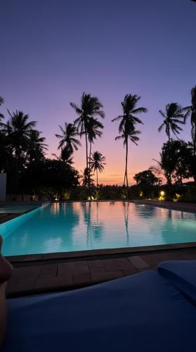 a large swimming pool with palm trees in the background at Serene Takaungu Hideaway with Private Pool, Near Kilifi in Takaungu