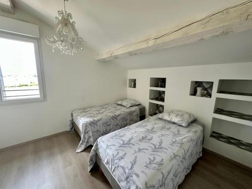 a bedroom with two beds and a chandelier at Mas de l Aire in Corneilla-del-Vercol