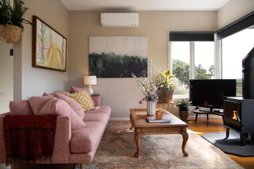 a living room with a pink couch and a tv at Treehouse Spa Villa - Unique & Secluded Retreat in Daylesford in Daylesford