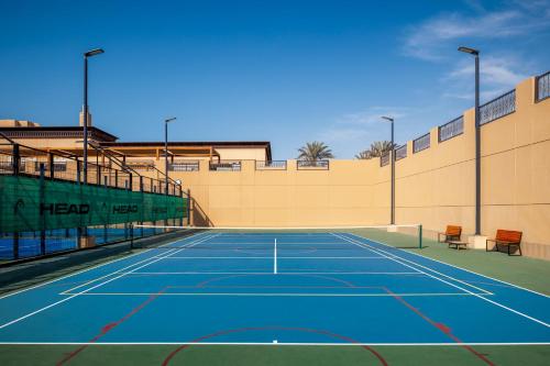 a tennis court with two benches on it at Saadiyat Rotana Resort and Villas in Abu Dhabi