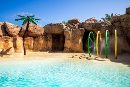 a beach with surfboards in the sand and a palm tree at Saadiyat Rotana Resort and Villas in Abu Dhabi