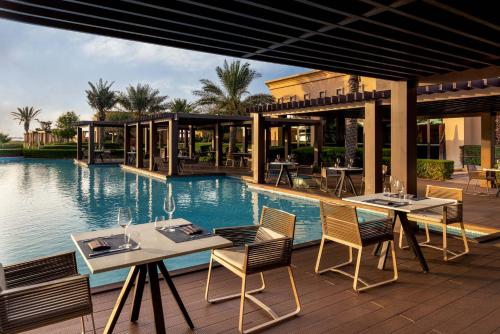 a patio with tables and chairs next to a pool at Saadiyat Rotana Resort and Villas in Abu Dhabi