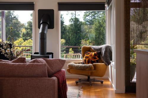 a living room with a chair and a wood stove at Treehouse Spa Villa - Unique & Secluded Retreat in Daylesford in Daylesford