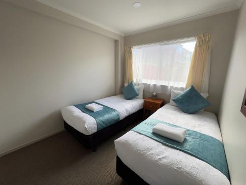 a small room with two beds and a window at Mountain View Motel in Taupo