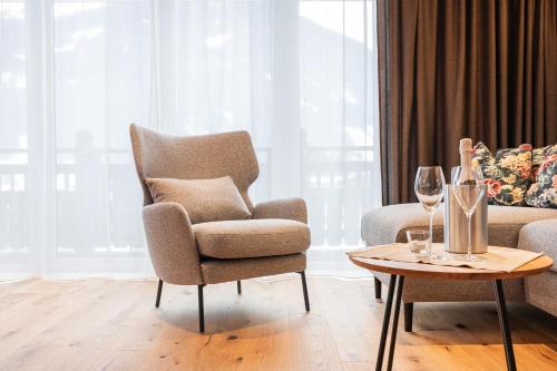a living room with a chair and a table with wine glasses at Apparthotel AlpenChalet in Neukirchen am Großvenediger