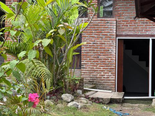 a brick building with a door in a garden at Lentera Lombok in Tetebatu