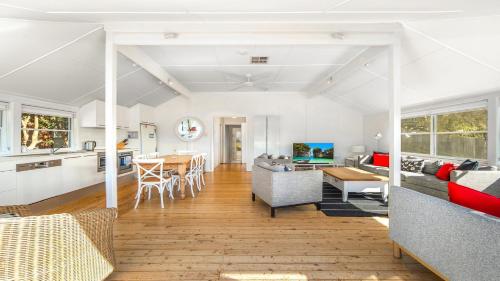 cocina y sala de estar con paredes blancas y mesa en 'Torcello - Waterfront on the Bay' by HolidayCo, en Hardys Bay