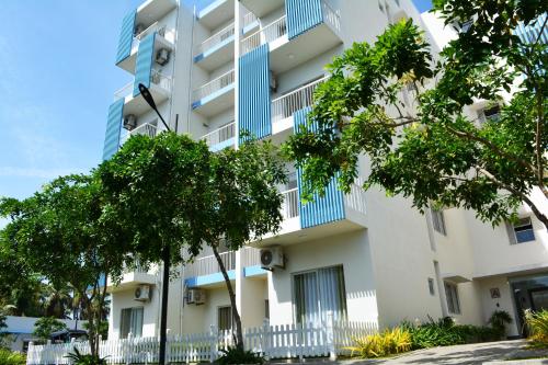 ネゴンボにあるSantorini Complex Apartment, Negombo by CM Holidayの青いバルコニーと木々のあるアパートメントビル