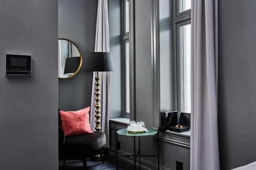 a room with a chair and a mirror and a table at Hotel Filip in Oslo