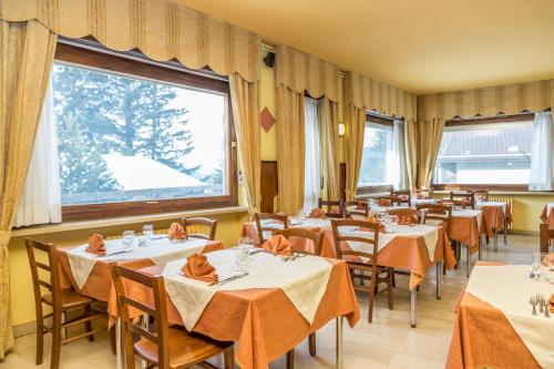 a dining room with tables and chairs and windows at Hotel La Terrazza in Sauze dʼOulx