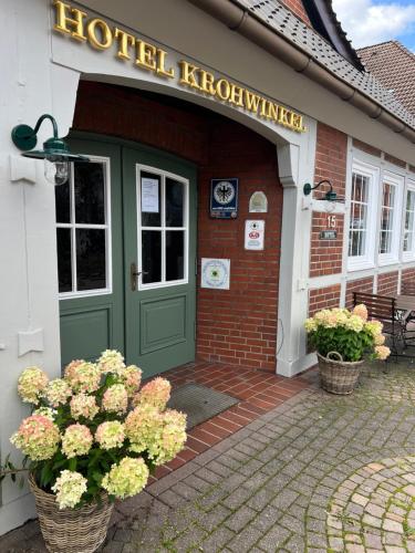 ヒットフェルトにあるHotel Krohwinkelの緑のドアと花が正面に飾られた建物