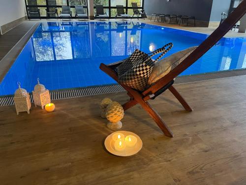 Un sillón reclinable con velas frente a una piscina. en B&B Self-Check-In GOLDENER HAHN - Hyggelige Budgetzimmer mit Panorama Hallenbad, en Baiersbronn