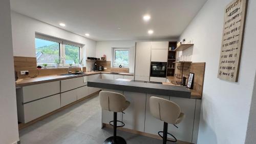 a large kitchen with a counter and two chairs at Ferienwohnung am Teufelsloch mit 2 Schlafzimmern und 2 Schlafcouchen a 1,4m in Altenahr