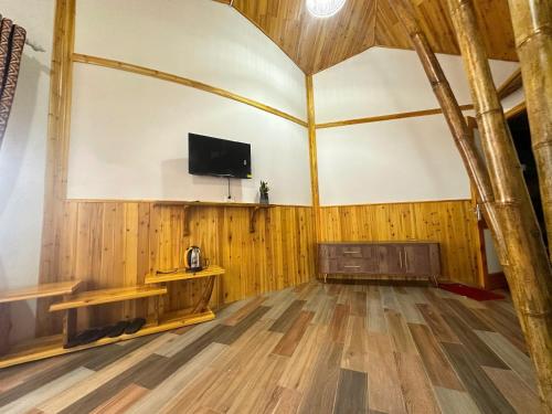 a room with a tv and a wooden floor at Long Cốc Ecolodge 