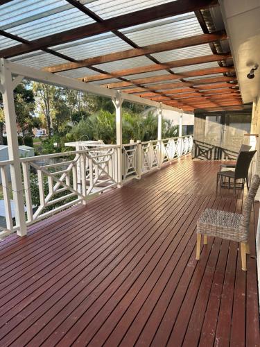 a wooden deck with chairs and a table on it at One Bedroom with shared bathroom and kitchen in Gold Coast