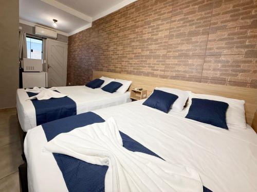 three beds in a room with a brick wall at Marmeu Tombo com Hidro Aquecida Privativa in Guarujá