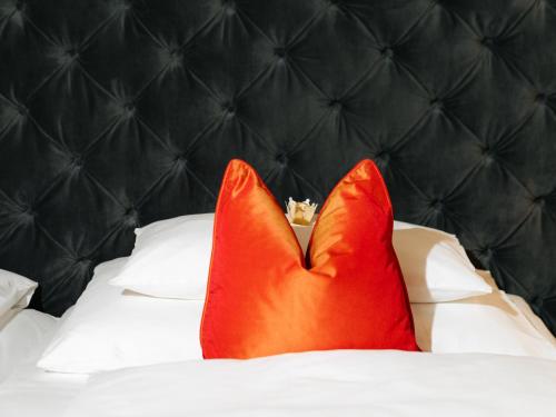 two red pillows on a bed with a black headboard at Hotel Kaiserhof Wien in Vienna
