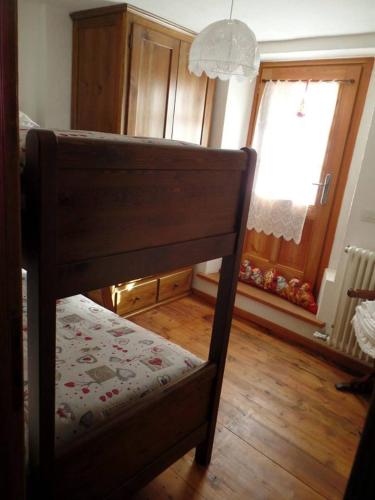 a bedroom with a bed with a wooden floor and a window at B&B Le Temps d'une Pause in Champorcher