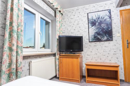 a bedroom with a tv and a bed and a window at Hotel Victory Home in Warsaw