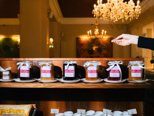 a person holding a spoon over a counter with bottles of sauce at Hotel Kaiserhof Wien in Vienna