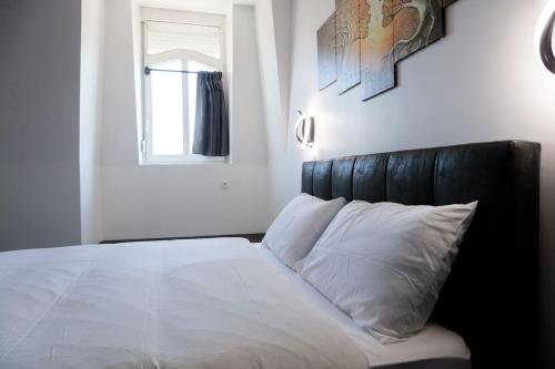 a white bed with a black headboard in a bedroom at SEE - Gare de Marly in Valenciennes