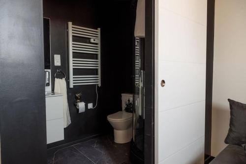 a bathroom with a toilet and a black wall at SEE - Gare de Marly in Valenciennes