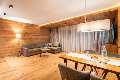 a living room with a table and a couch at Apparthotel AlpenChalet in Neukirchen am Großvenediger