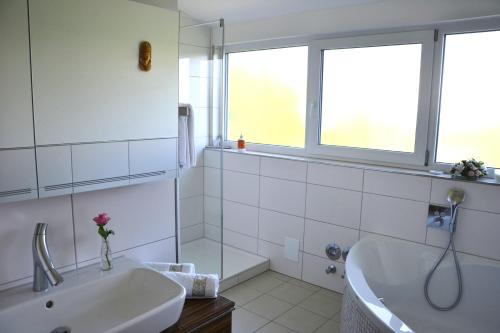 een witte badkamer met een bad en een wastafel bij Ferienwohnung Am Bergle in Überlingen