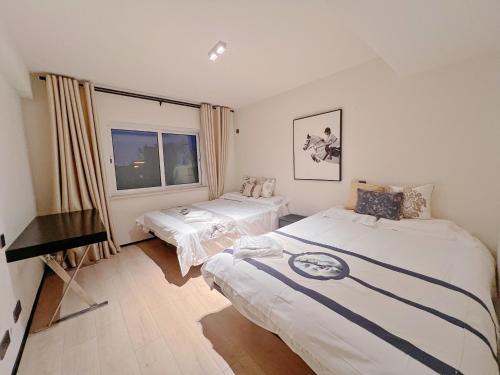 a bedroom with two beds and a window at Yu Garden Riverside Retreat 3BR with Latex Mattresses in Shanghai