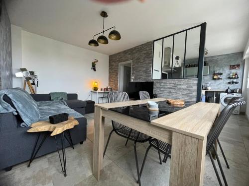 a living room with a table and a blue couch at Le coin des voyageurs in Chalon-sur-Saône