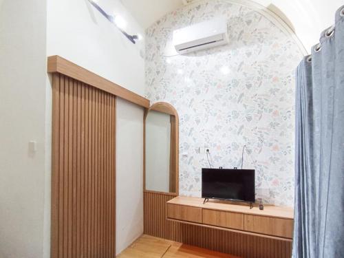 a bathroom with a mirror and a tv on a wall at Urbanview Hotel Trisna Srabah in Kalangbret