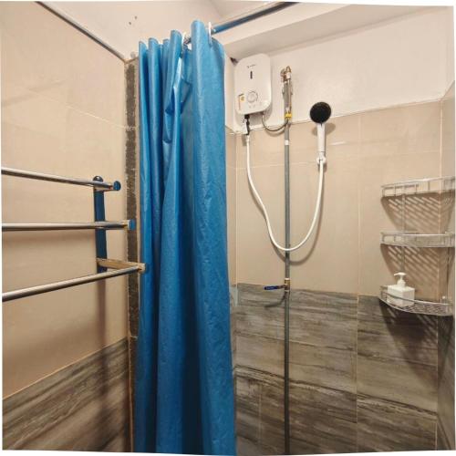 a shower with a blue curtain in a bathroom at AV Suites in Puerto Galera