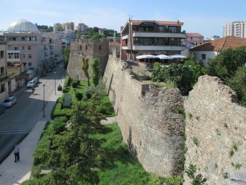 an old stone wall next to a street and buildings at Golem Flower Roof top private terrace in Golem