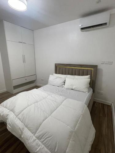 a bedroom with a large bed with white sheets at Modern 2-Bedroom Apt in Lifecamp in Tungan Daudu