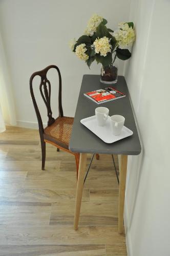 a table with two cups and a vase with flowers at AL 32 B&B in Massa Marittima