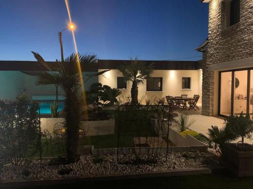 une maison avec une cour avec des palmiers et un lampadaire dans l'établissement VILLA de Standing, 10 personnes, Piscine, Spa à 200m des plages, à Brignogan-Plage