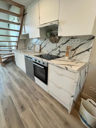 a kitchen with white cabinets and marble counter tops at Appartement Duplex -Vue sur mer- à 100 m de la plage in Le Portel