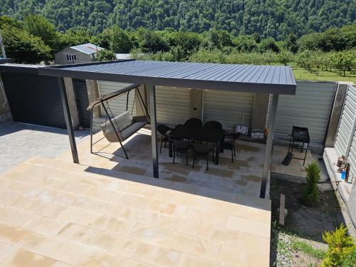 a pavilion with a table and chairs on a patio at Pine Barn House in İsmayıllı