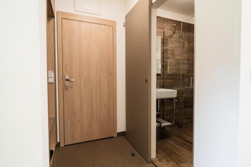 Un baño con puerta de madera y lavabo. en Hotel Stubnerhof, en Bad Gastein