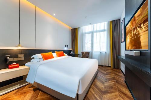 a bedroom with a large white bed and a tv at HeSu Hidden Art Hotel & Suites - Near Bell Tower & Ideal Location-Spacious rooms featuring King or Double Queen beds -Exclusive Two&Three-Bedroom Suites with Expansive Living Rooms for Group Gathering-Kitty Cuddles & Coffee Gift -Seamless Journey Planning in Xi'an