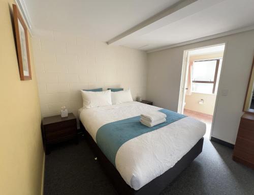 a bedroom with a large bed with towels on it at Mountain View Motel in Taupo