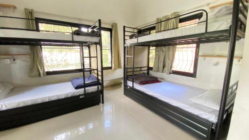 two bunk beds in a room with two windows at Lifespace- Spacious Hostel in a Luxurious Villa in Pune