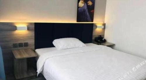 a bedroom with a large white bed and two lights at 7 Days Inn Changzhou Yancheng Technology Metro Station in Changzhou