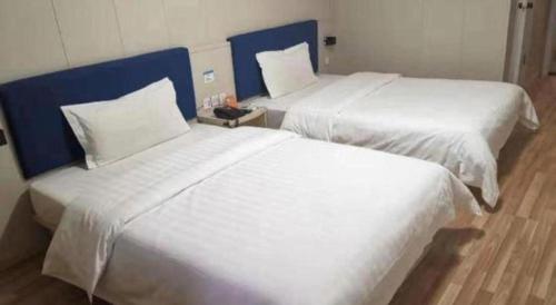 two beds in a hotel room with white sheets at 7 Days Inn Changzhou Yancheng Technology Metro Station in Changzhou