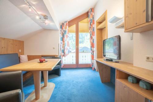 a living room with a table and a television at Hotel Garni Austria in Ischgl