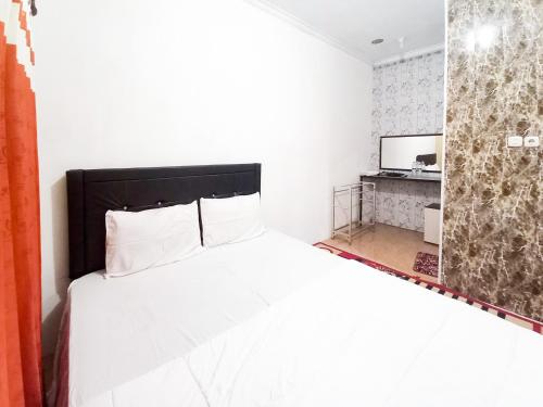 a bedroom with a white bed and a television at Lancar Homestay Syariah near BNS Mitra RedDoorz in Tlekung