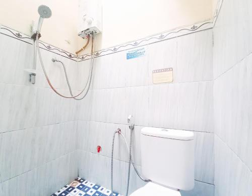 a white bathroom with a shower and a toilet at Lancar Homestay Syariah near BNS Mitra RedDoorz in Tlekung