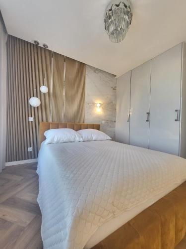 a bedroom with a large white bed with a chandelier at Apartaments by Ola in Radom