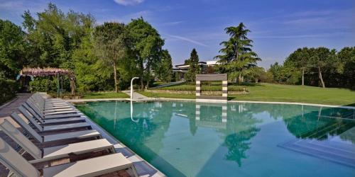 a large swimming pool with lounge chairs in a yard at Hotel Mioni Pezzato in Abano Terme