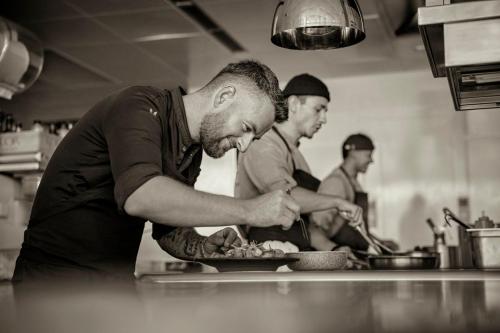 a group of men preparing food in a kitchen at COMO Alpina Dolomites in Alpe di Siusi